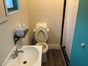 Ein Badezimmer mit einem weißen Waschbecken, einer Toilette und einem kleinen Fenster.