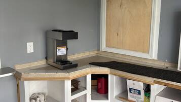 Habitación de esquina con escritorio empotrado, una pelota de baloncesto, cafetera y cajas de almacenamiento.