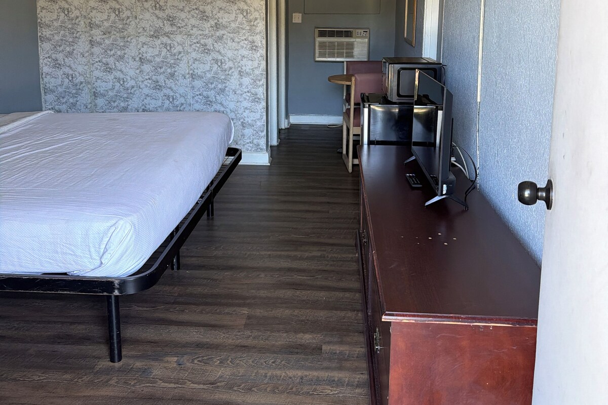 Quarto de hotel com cama, penteadeira, escrivaninha e ar condicionado.