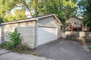 Ein eingeschossiges Gebäude mit Garage, umgeben von einem Holzzaun und Bäumen.