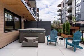 Een terras met een hottub, Adirondack stoelen en een kleine tafel.