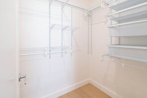 Een kamer met witte muren, een houten vloer en metalen schapkasthouten rekken.