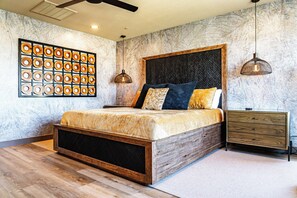 Une chambre à coucher moderne avec un lit en bois, un mur en marbre et une œuvre d’art murale circulaire originale.