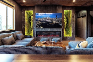 Un salon moderne doté d’un grand téléviseur à écran plat fixé sur un mur en pierre, d’un confortable ensemble de canapés et d’une table basse en bois.