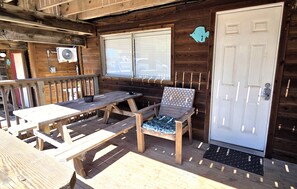 A wooden deck with a table and chairs, a door, and a window with blinds. - BC7--Studio Sleeps 2 Adults/2 Kids, Walk to Beach, Pool/Hot Tub, Dogs OK! (Port Aransas)