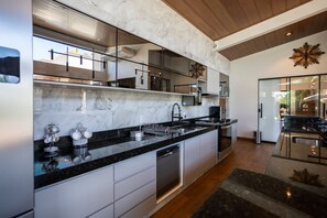 A modern kitchen with a marble countertop, stainless steel appliances, and a built-in dishwasher. - Ch Cara com Piscina Hidro e Lago em Trindade - GO (Goiânia)