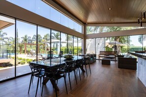 A spacious indoor area with a large dining table, chairs, and a seating area with a bench and cushions. - Ch Cara com Piscina Hidro e Lago em Trindade - GO (Goiânia)