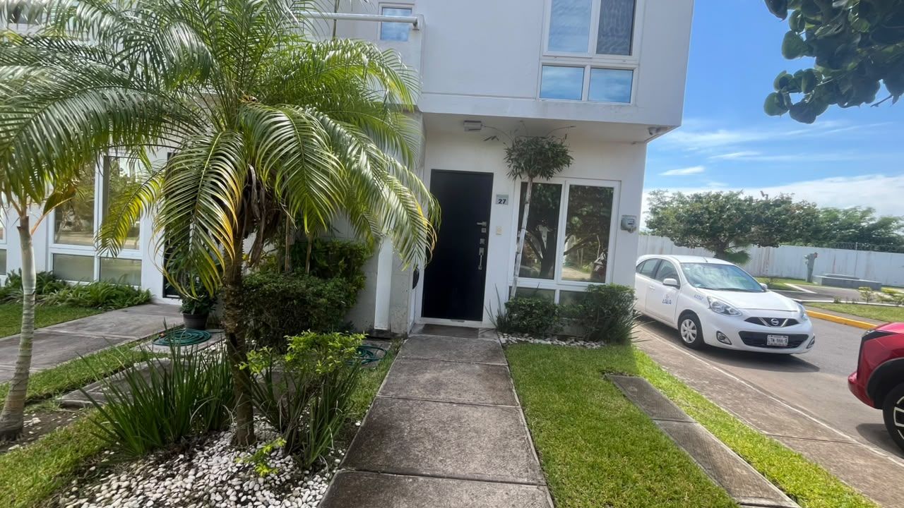 A modern building with a front entrance, a driveway, and a parked car.
