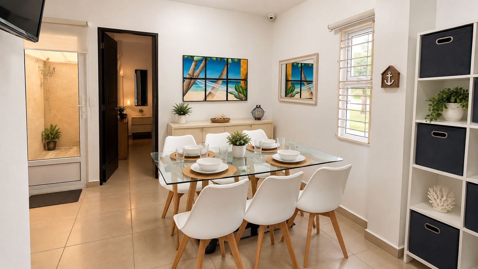 Un comedor moderno con una mesa de vidrio, sillas blancas y vista al mar a través del ventanal.