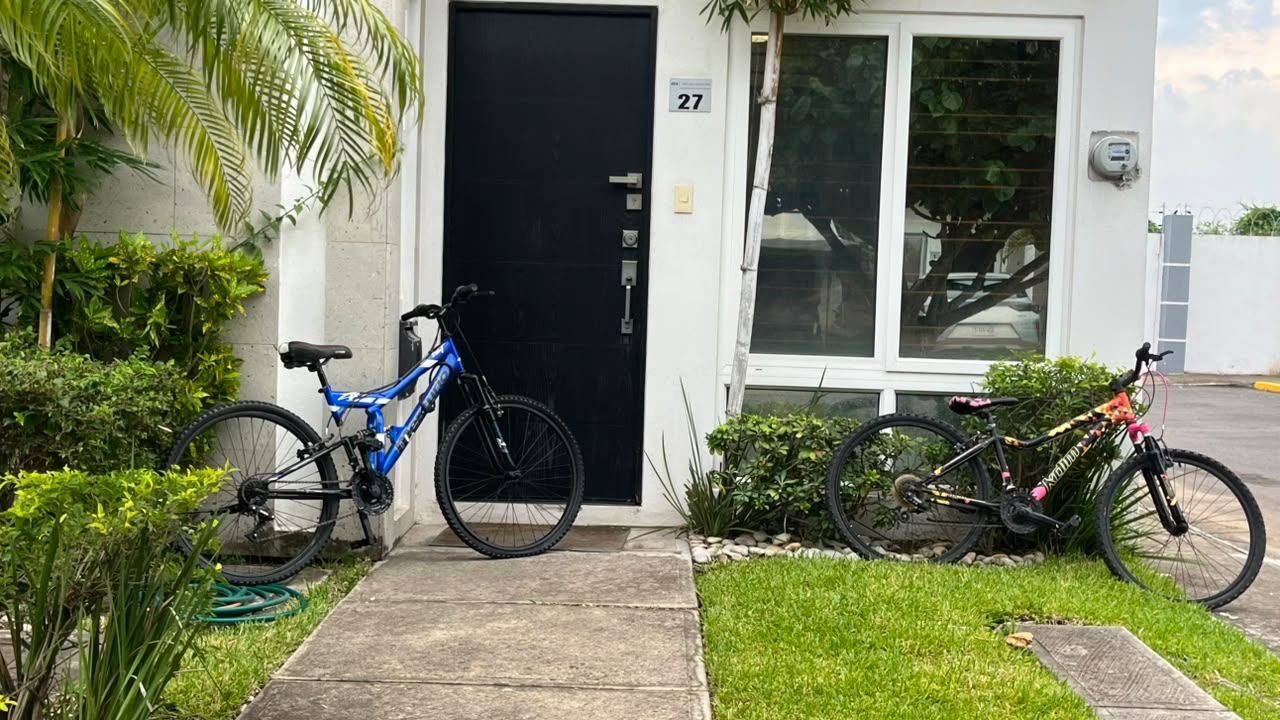 Un edificio residencial con una puerta negra, el número 27, y dos bicicletas estacionadas afuera.