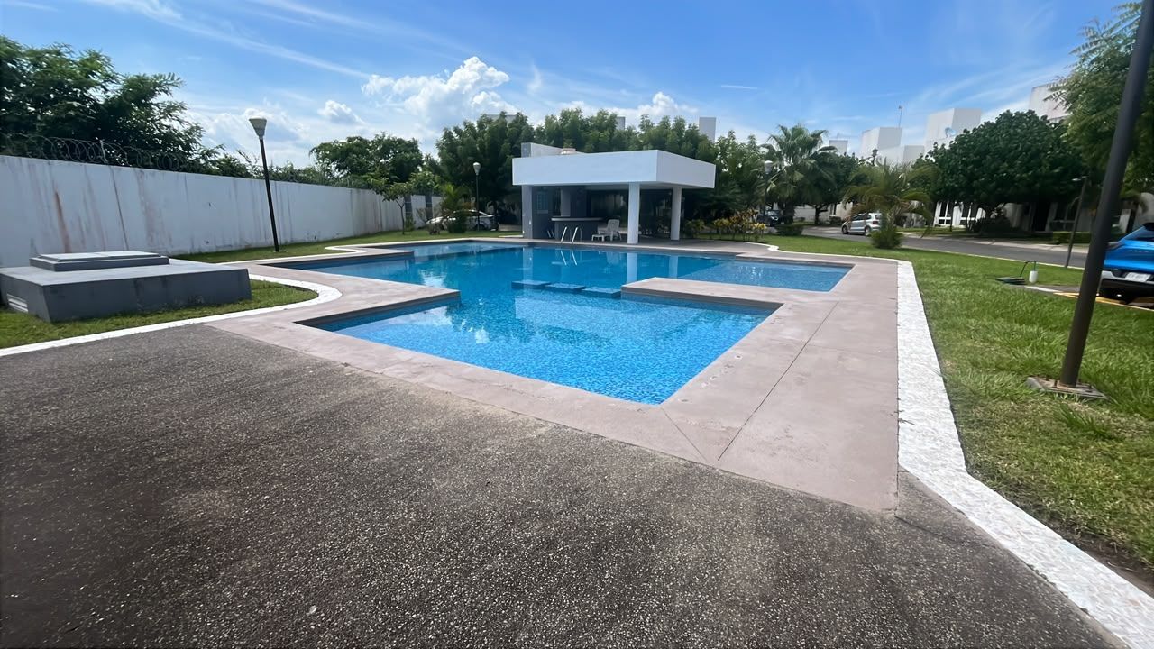 A rectangular swimming pool with a white structure in the background.