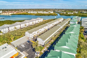 Eine lange Reihe weißer Gebäude mit grünen Dächern, neben einem Gewässer, vermutlich einem Yachthafen.
