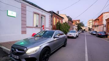 Rua com carros estacionados, incluindo um Mercedes-Benz prateado.