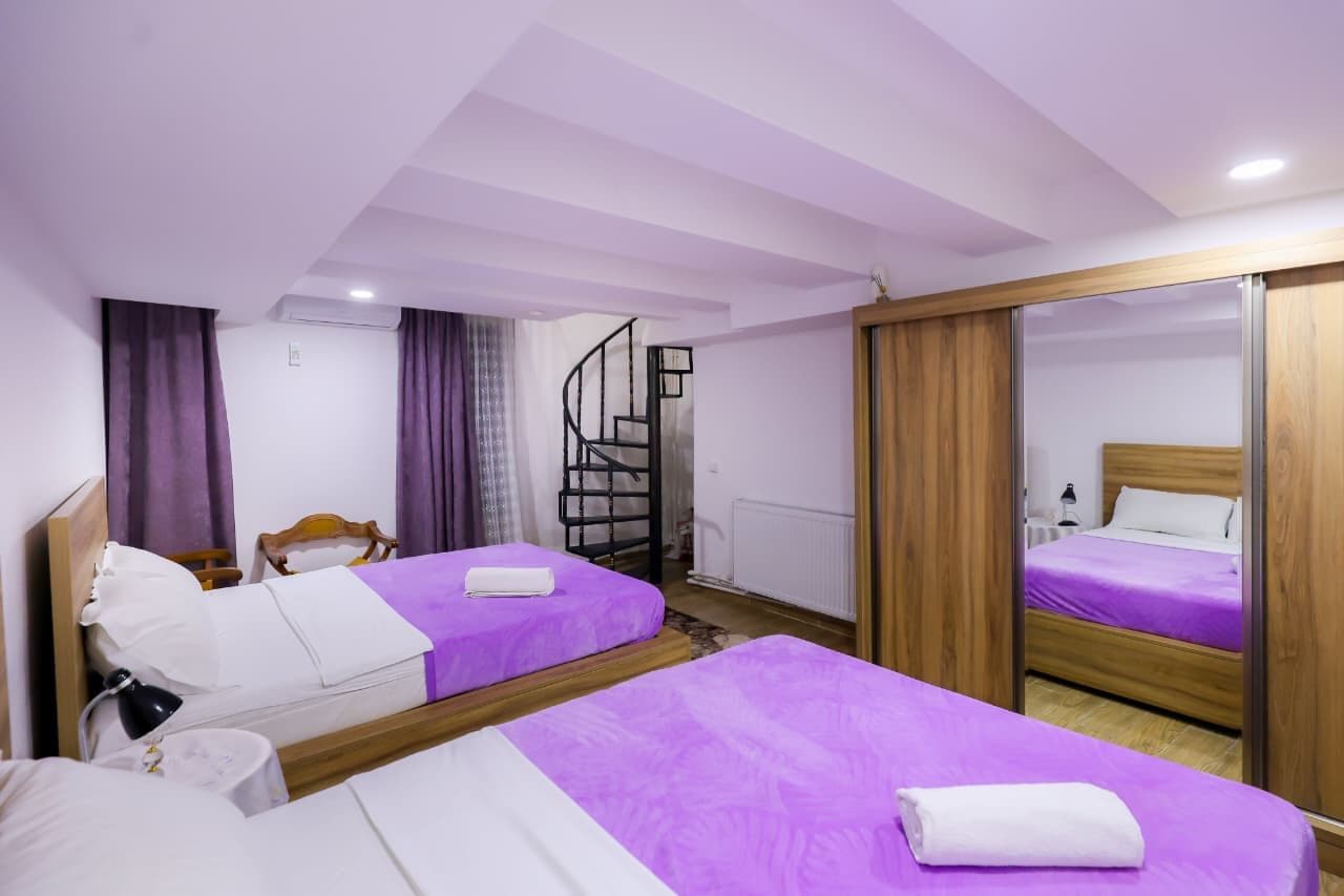 Een hotelkamer met twee bedden, een houten kast, een spiegel en een trap.