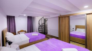 Een hotelkamer met twee bedden, een houten kast, een spiegel en een trap.