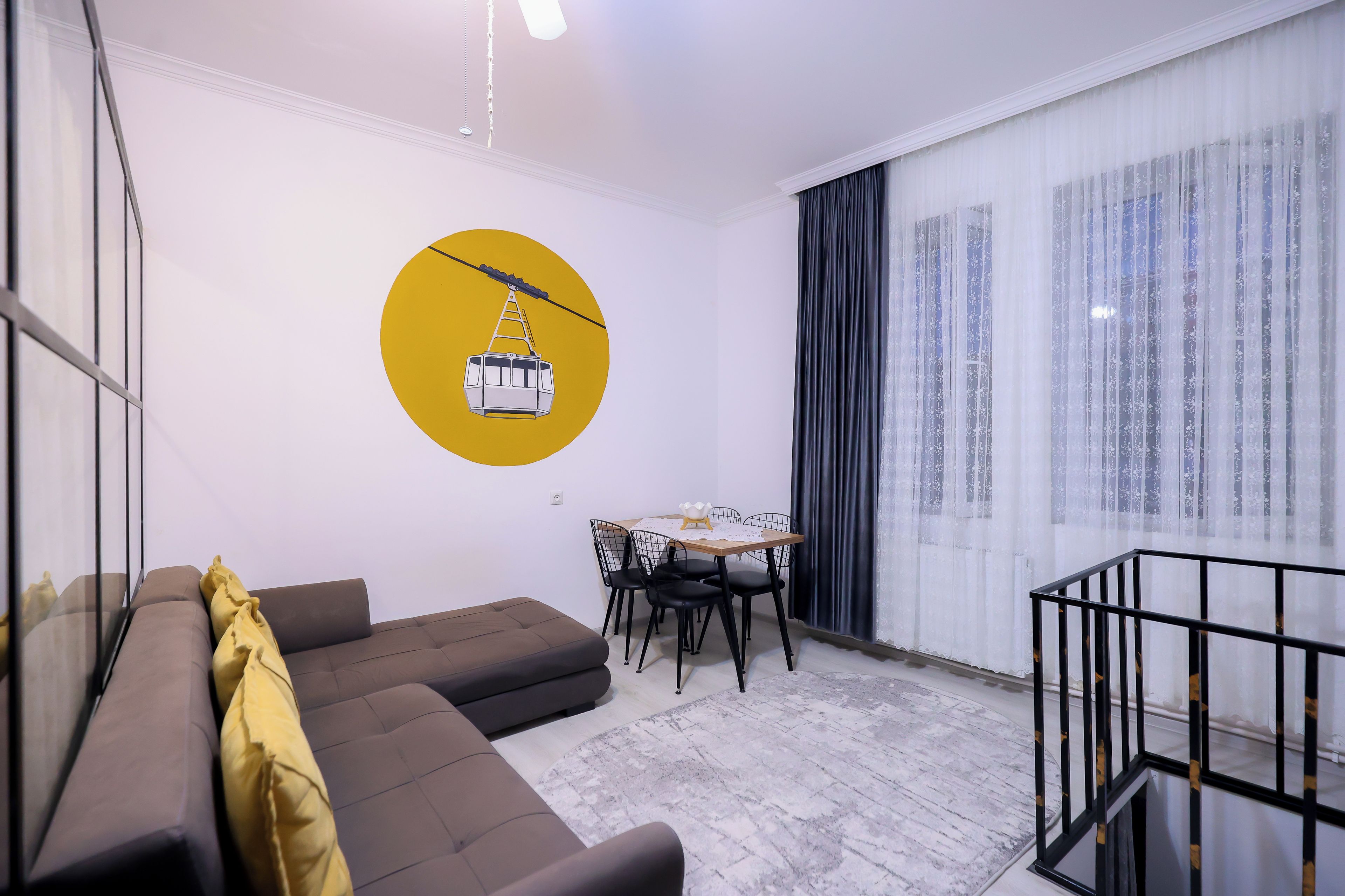 Una sala de estar moderna con un sofá, una mesa de comedor con sillas y un ventanal con cortinas.