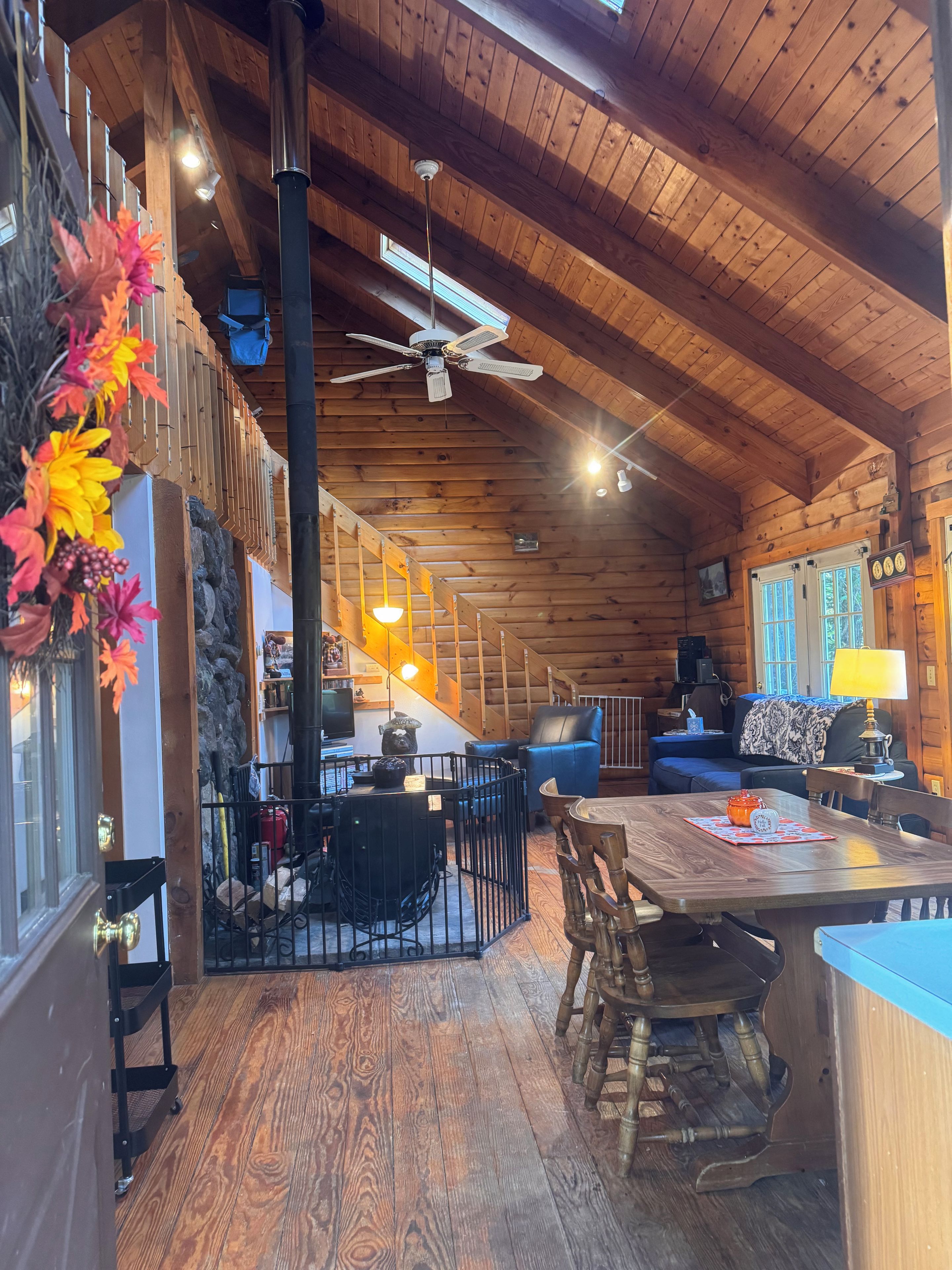 A wooden cabin interior with a dining area, kitchen, and seating space.