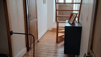 Una escalera de madera con barandilla, una puerta con sistema deslizante y una mesita con un marco de fotos.