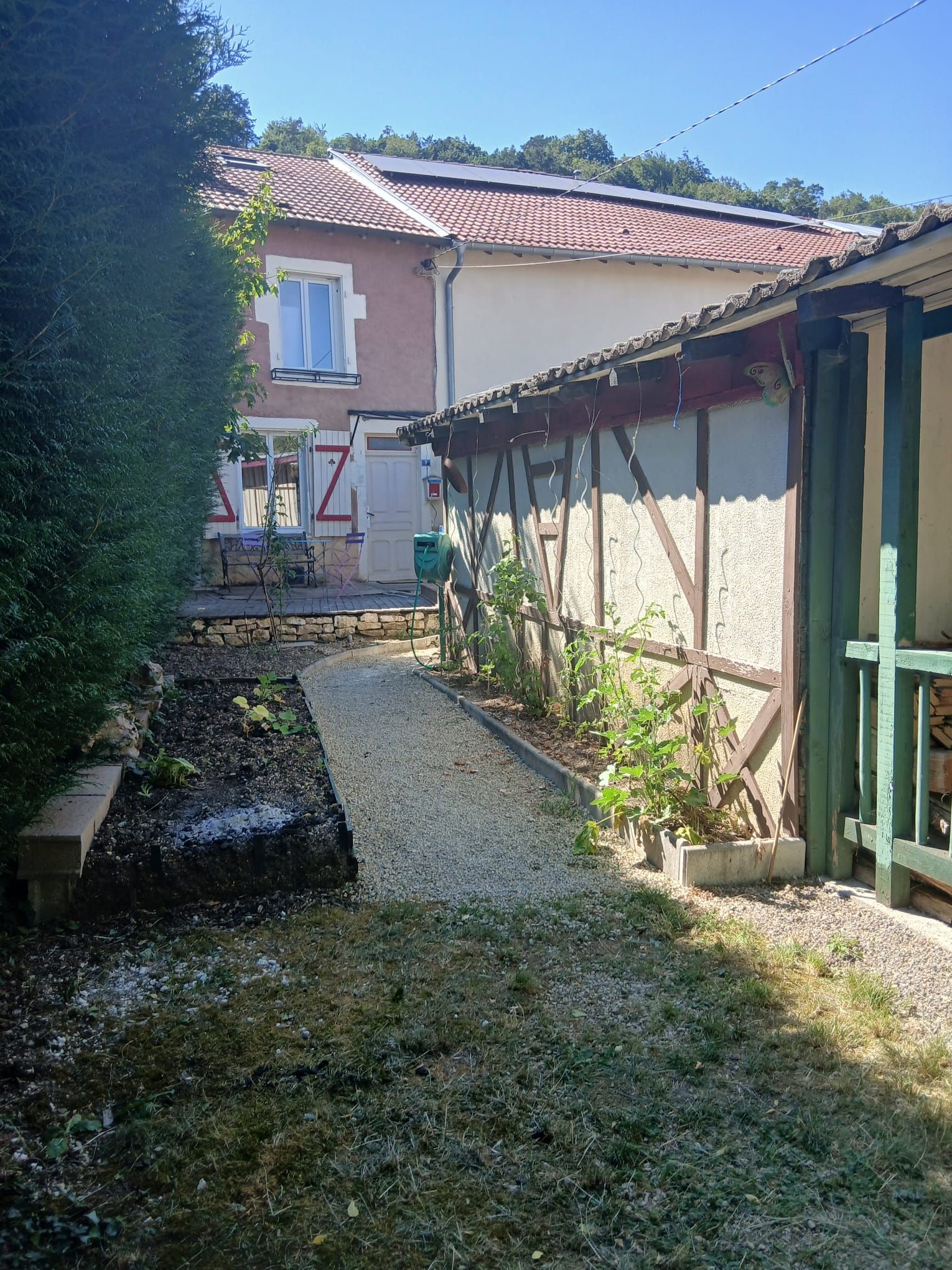 Um imóvel residencial com um caminho de pedrisco, área de jardim e casa com telhado em telhas.