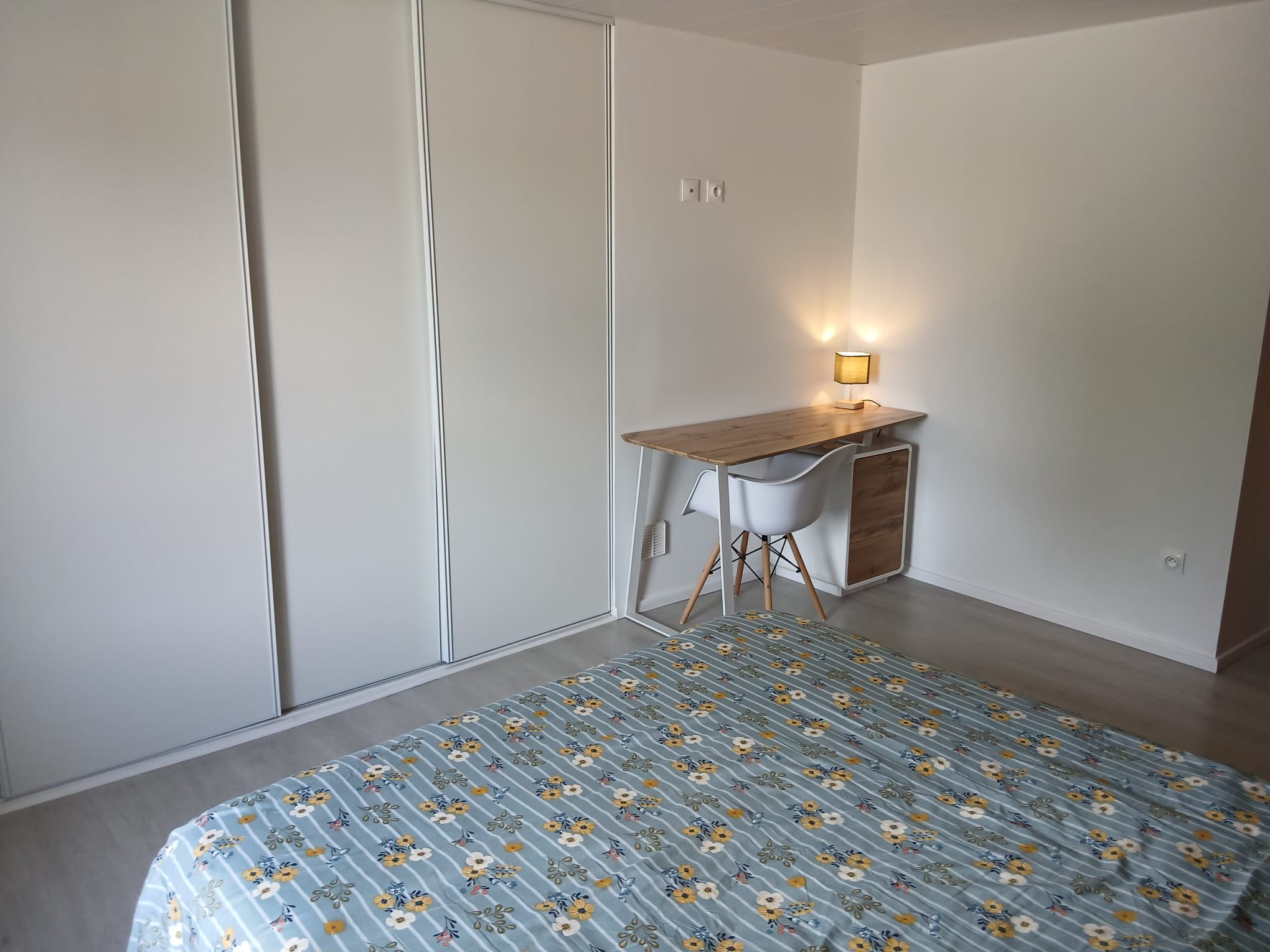 Een slaapkamer met een bed, een bureau en een stoel.
