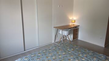 Een slaapkamer met een bed, een bureau en een stoel.