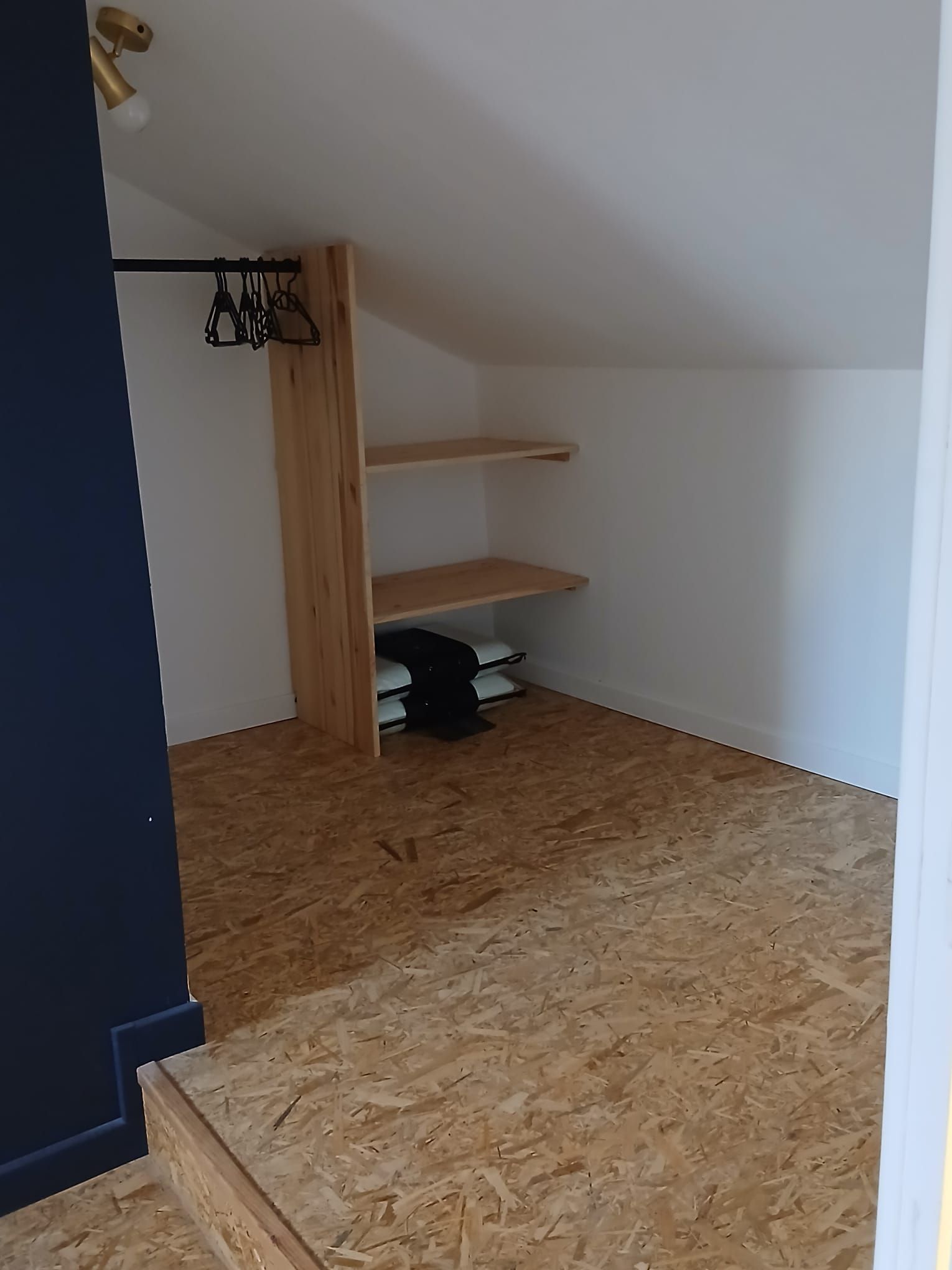 Een kamer met een schuine kap, houten vloer en inbouwkasten.