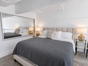 Une chambre à coucher moderne avec un grand lit, des lampes de chevet et un grand miroir.