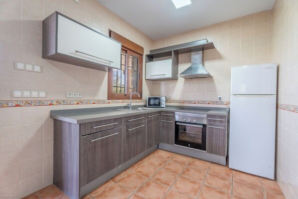 A kitchen with a built-in oven, a microwave, and a refrigerator. - Vrbo Property (Coin)