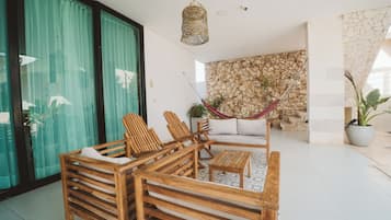 Un salon moderne avec des meubles en bois, un mur en pierre et un hamac.