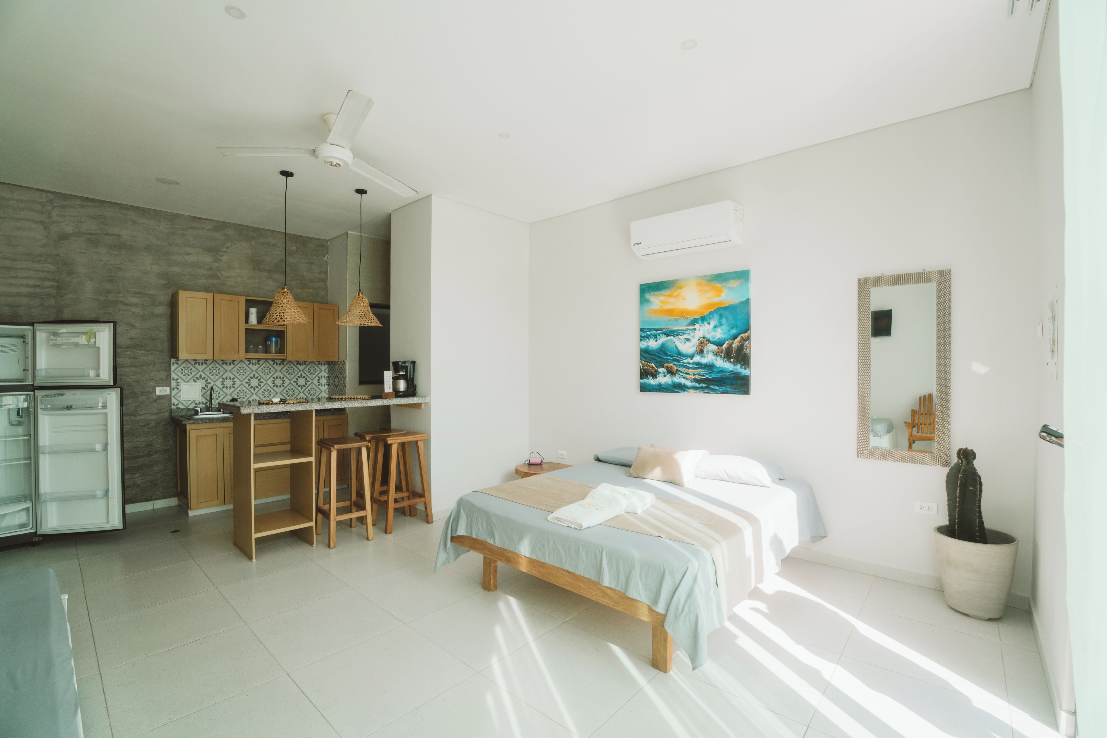 A modern kitchen with a dining area, a bed with a view, and a cactus plant.