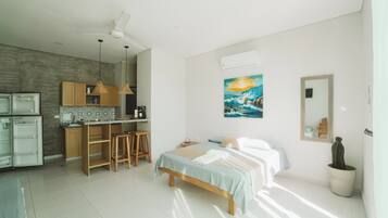 A modern kitchen with a dining area, a bed with a view, and a cactus plant.