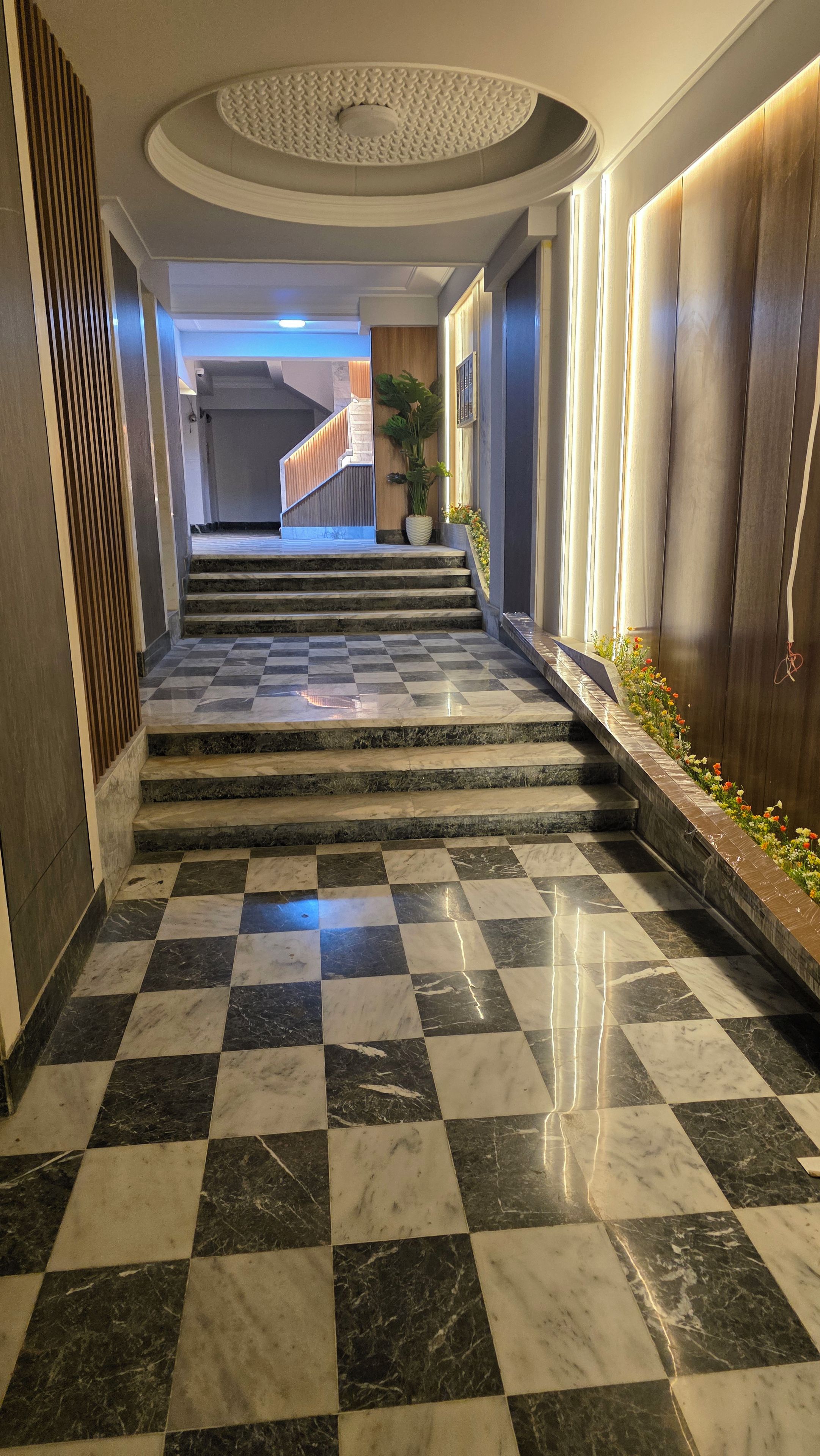 A marble-floored hallway leading to a staircase with a checkered pattern.