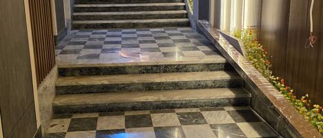 A marble-floored hallway leading to a staircase with a checkered pattern.