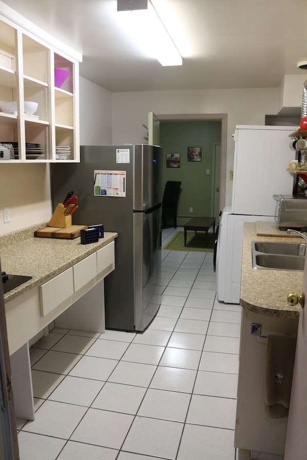 Una cocina con refrigerador, pileta y encimera con un bloque para cuchillos.
