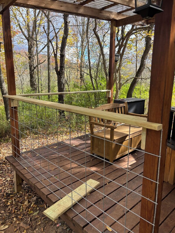 A wooden deck with a metal railing, a bench, and a table.