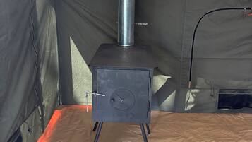 Un poêle portatif doté d’une cheminée, d’une porte avec une poignée et d’une ouverture de ventilation sur le côté.