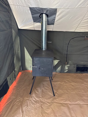 En portabel kamin med en skorsten, en dörr med ett handtag och en ventil på sidan.