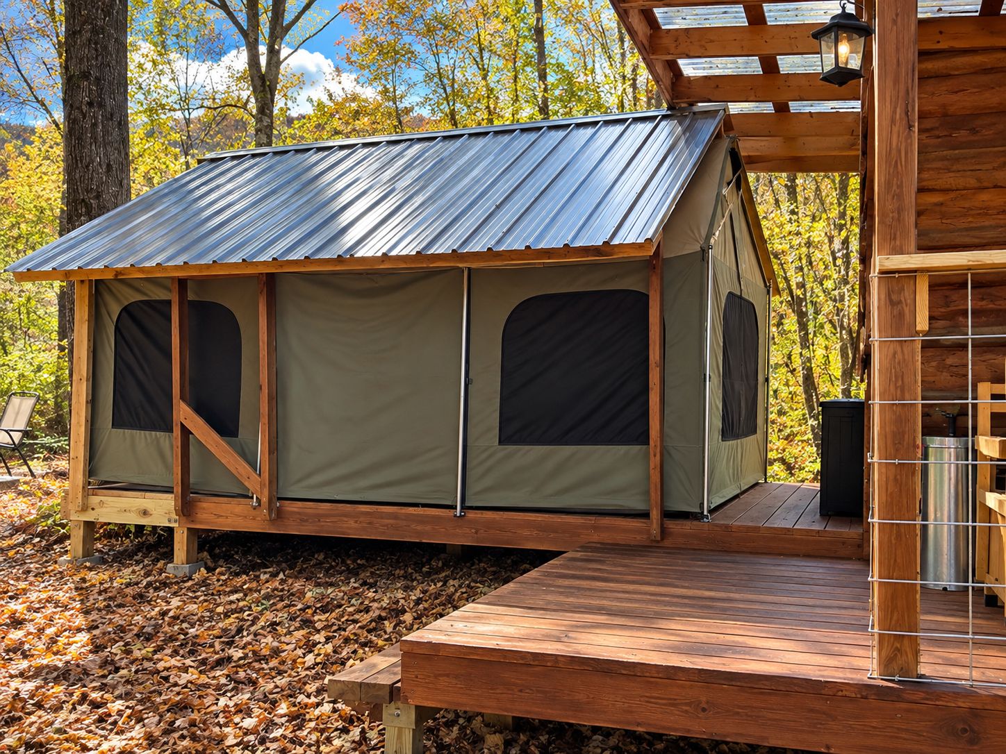 Une cabane en bois avec un toit en métal, une terrasse et une structure ressemblant à une tente, dotée de fenêtres.