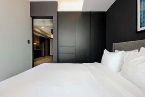 A modern hotel room with a large bed, built-in wardrobe, and a view of the hallway. - w* | Thoughtful 2BR w/ Balcony in Tabacalera (Ciudad de México)