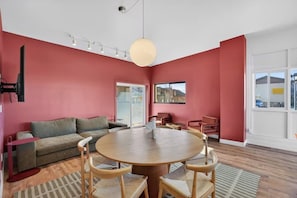 A modern living room with a round wooden table, a grey sofa, and a red accent wall. - Highlander Room 3 Cozy Private Room in Williams (Williams)