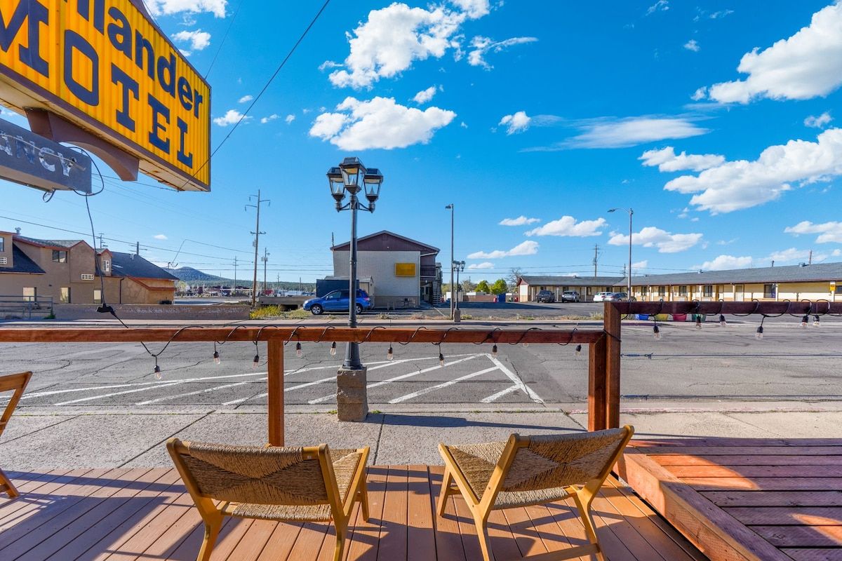 A motel with a clear view of the parking lot and a signboard.