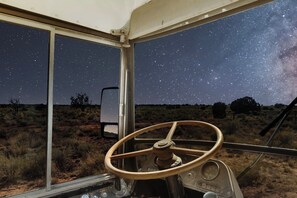 A steering wheel and a window with a starry night sky view. - Glamping Bus | Milky Way Views (Williams)