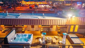 Eine Dachterrasse mit Whirlpool, Liegestühlen und einem Feuerkorb.
