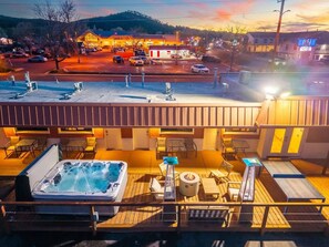 Een terras op het dak met een jacuzzi, lounge stoelen en een vuurkuil.