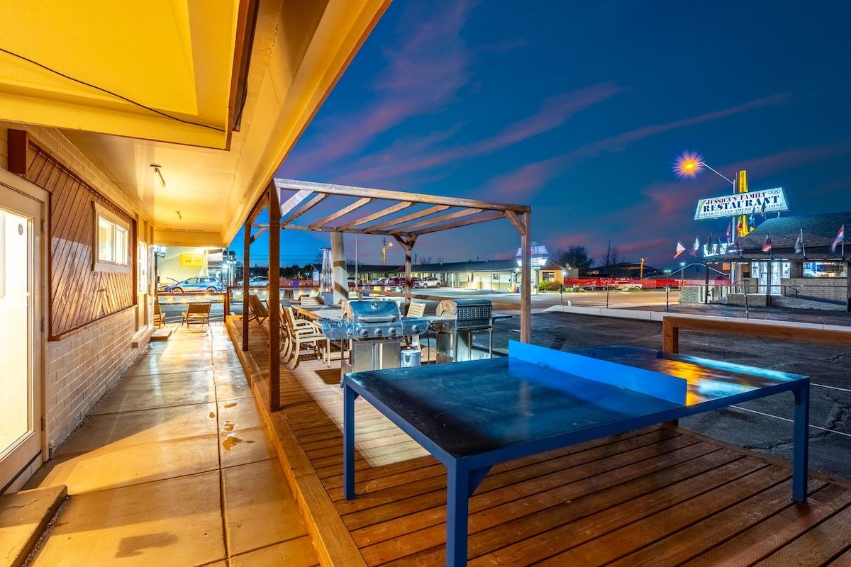 An outdoor patio area with a covered seating area, barbecue grill, and a table.