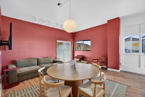 A modern living room with a round wooden table, a sofa, and a television.