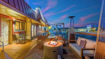 A deck with outdoor seating, a fire pit, and a view of the water.