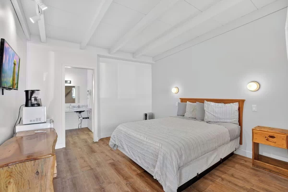 Un dormitorio con cama, mesita de noche y cómoda de madera.