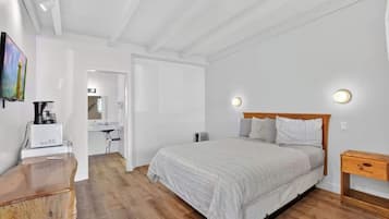 Un dormitorio con cama, mesita de noche y cómoda de madera.