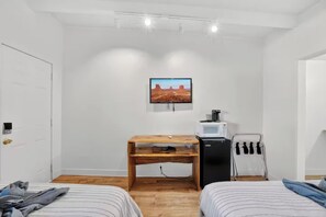 A room with two beds, a wooden desk, a television, a microwave, and a towel rack. - Highlander Room 4 Cozy Private Room in Williams (Williams)
